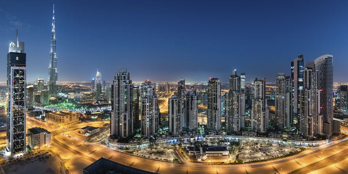 Cityscape of Dubai, United Arab Emirates, at dusk, with illuminated skyscrapers in the foreground