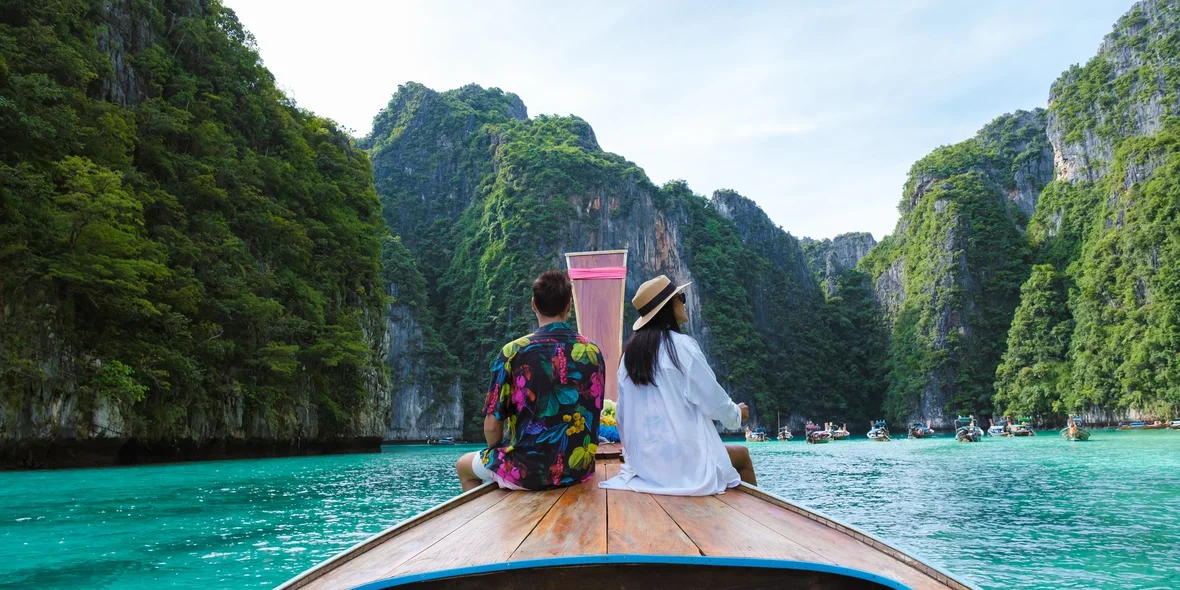 A couple in front of a longtail boat in the lagoon of Phi Phi Phi Island, Thailand
