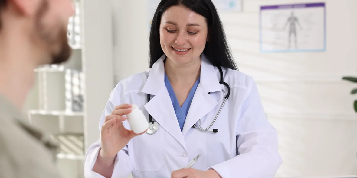 Doctor with bottle of pills consults patient at table in hospital