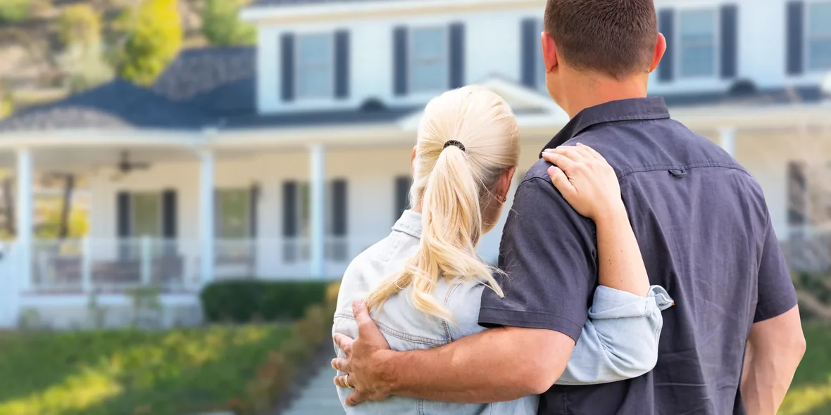 Young adult couple in front of a beautiful home.