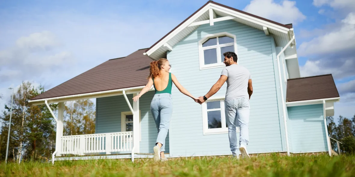 A man and a woman holding hands outside a house