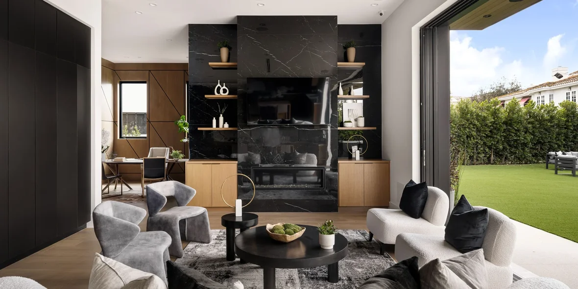 Modern living room with black marble fireplace and backyard view