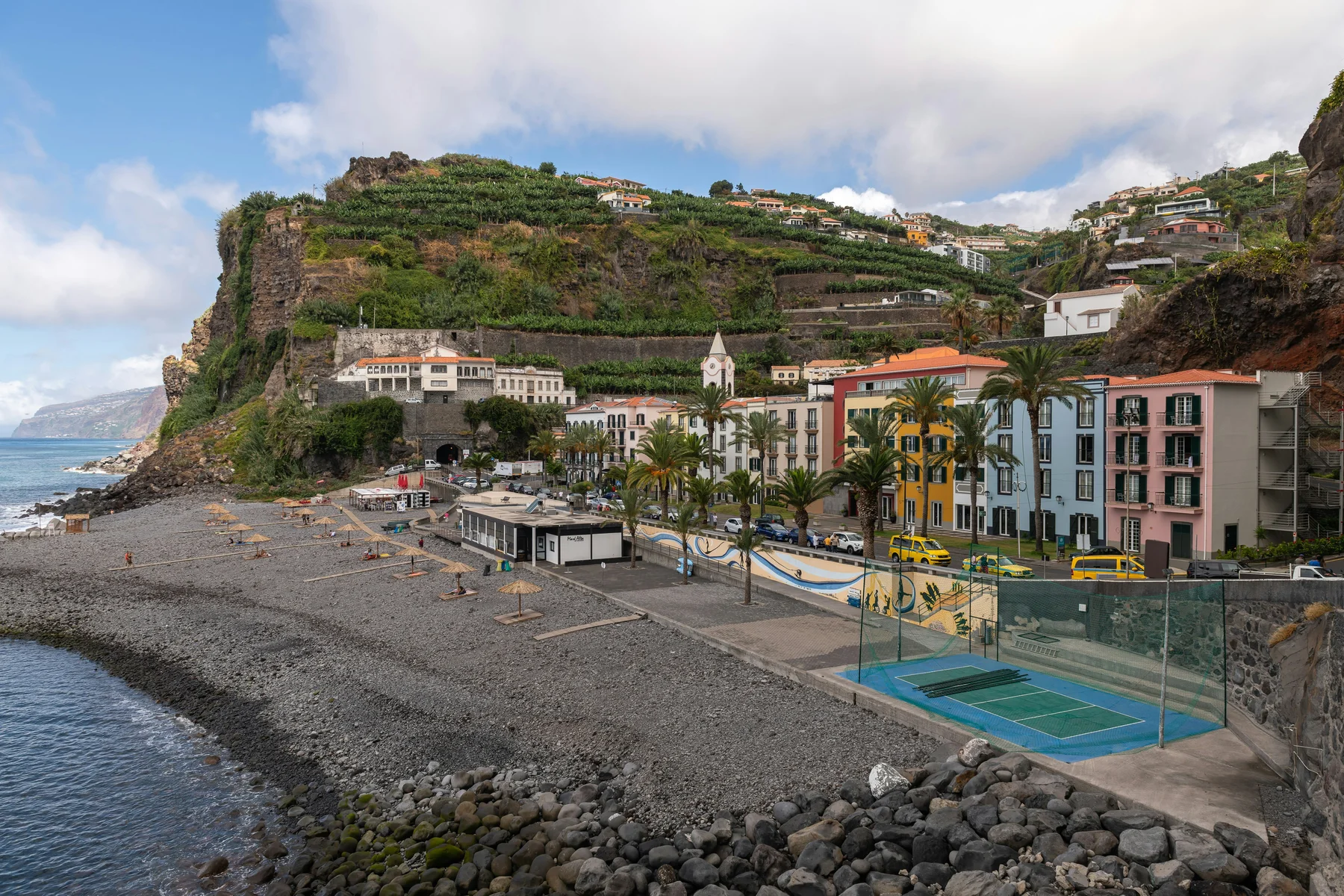 a tennis court on a rocky beach next to the ocean