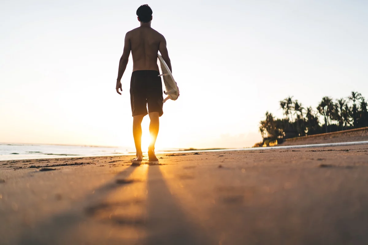 Ein Mann geht mit einem Surfbrett zum Meer