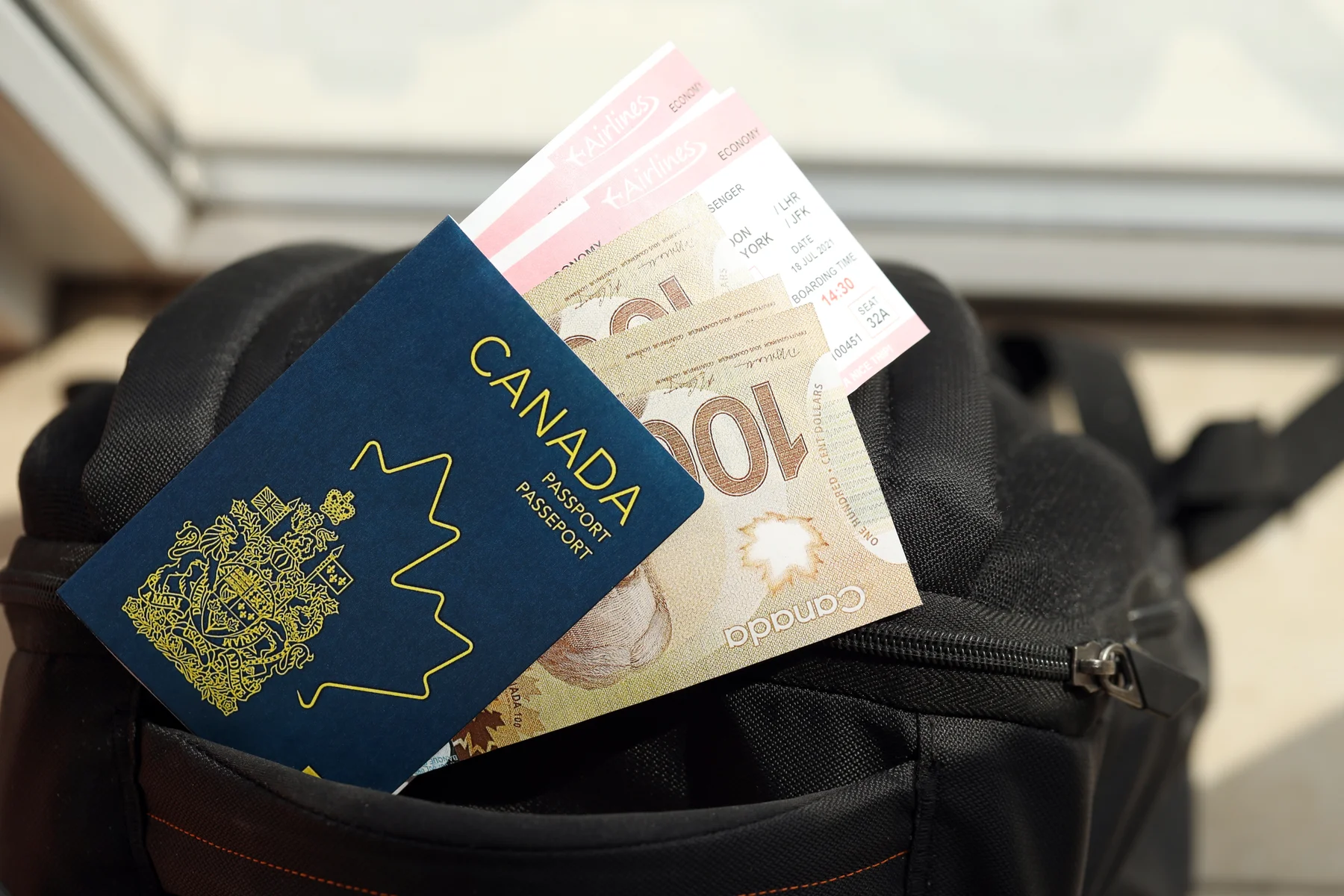 Canadian passport against a backdrop of banknotes and airline tickets