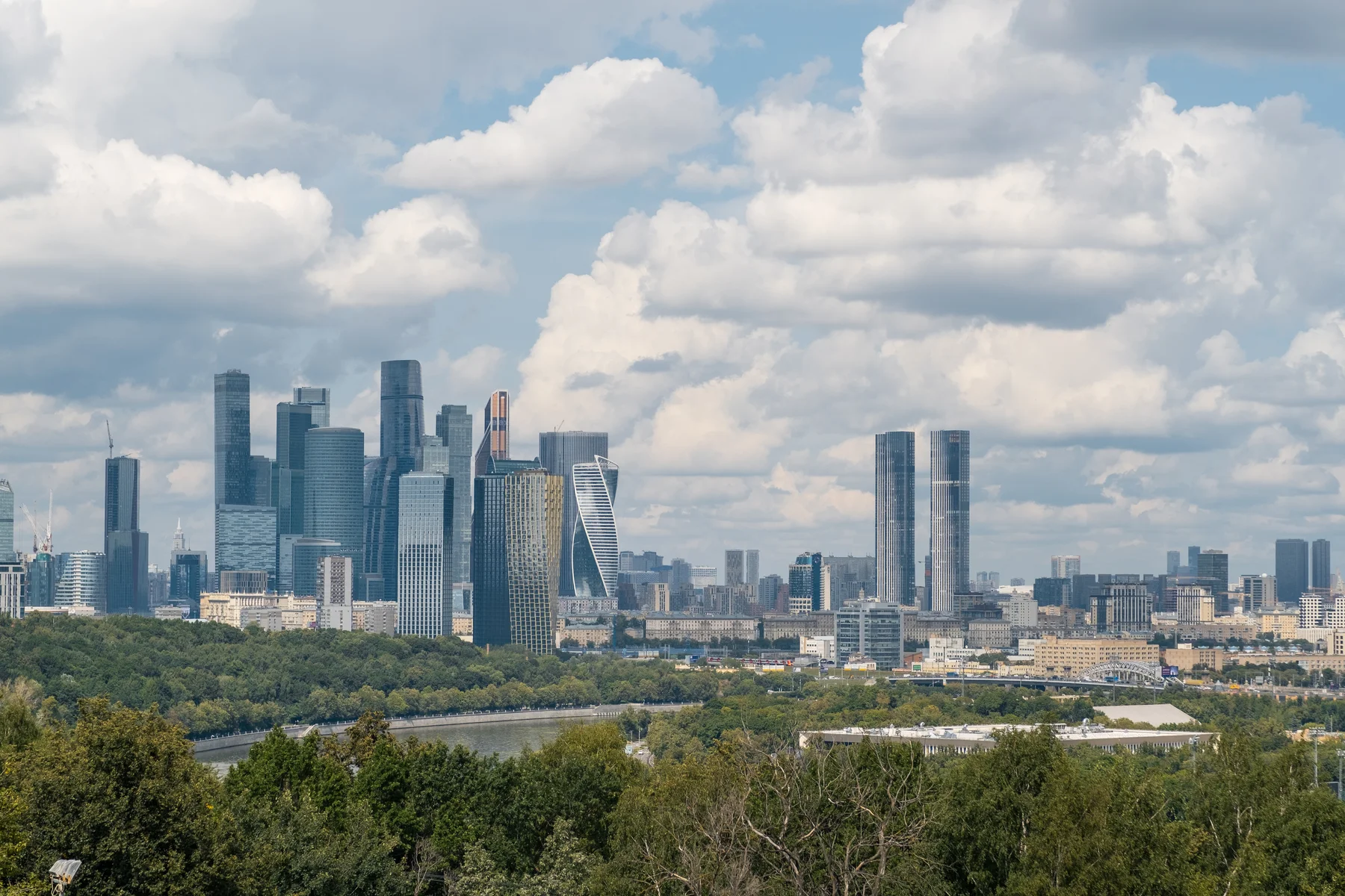 Посетители наслаждаются пышной зеленью парка Лужники, любуясь впечатляющим пейзажем Москвы