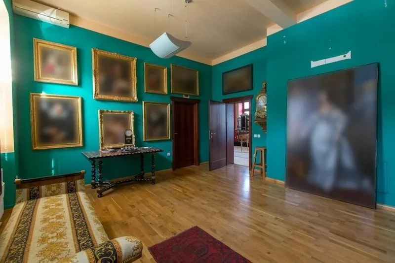 Turquoise walls and lots of paintings in a room of an old manor house in Slovenia